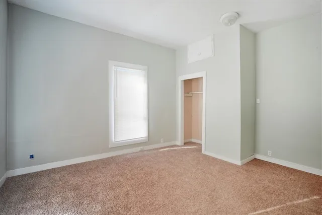 a view of an empty room with closet and a window