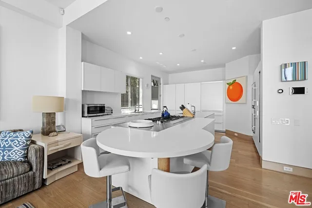 a living room with stainless steel appliances furniture a rug and a kitchen view