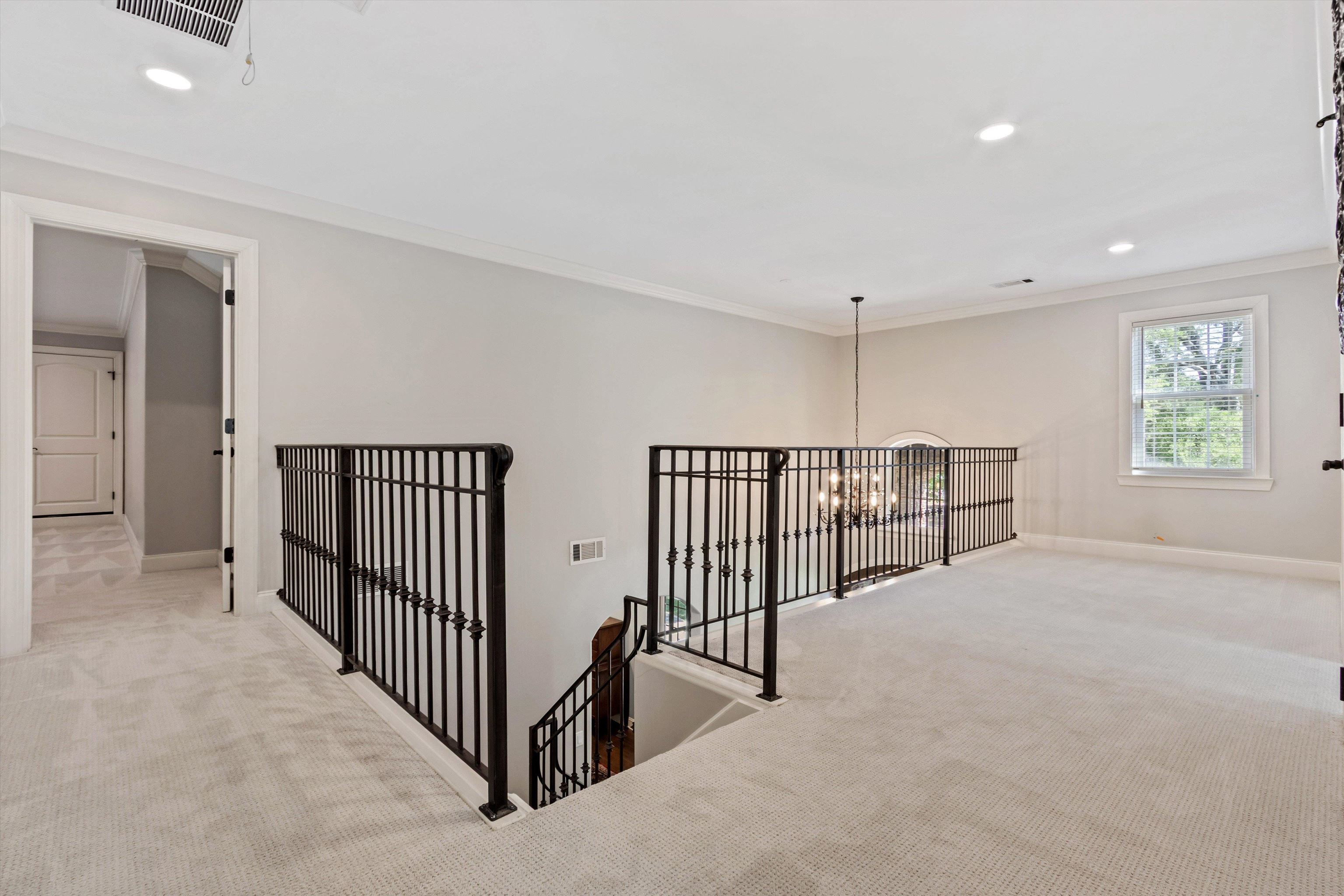 5302 South Angela Road Memphis, TN 38120 - Photo 27 of 40 Expansive carpeted loft area featuring wrought iron railings, an arched window, and recessed lighting