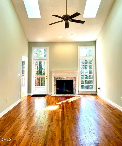 a view of empty room with wooden floor and fan