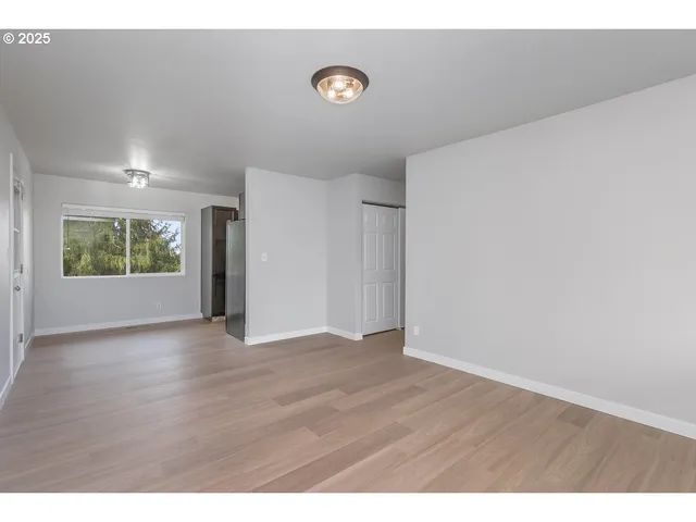 a view of an empty room with a window and wooden floor