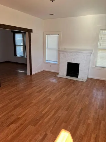 a view of empty room with wooden floor and fireplace
