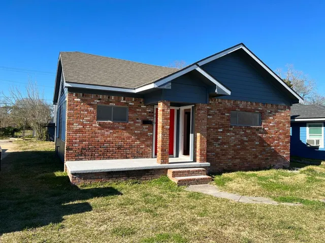 a view of a house with wooden fence next to a yard