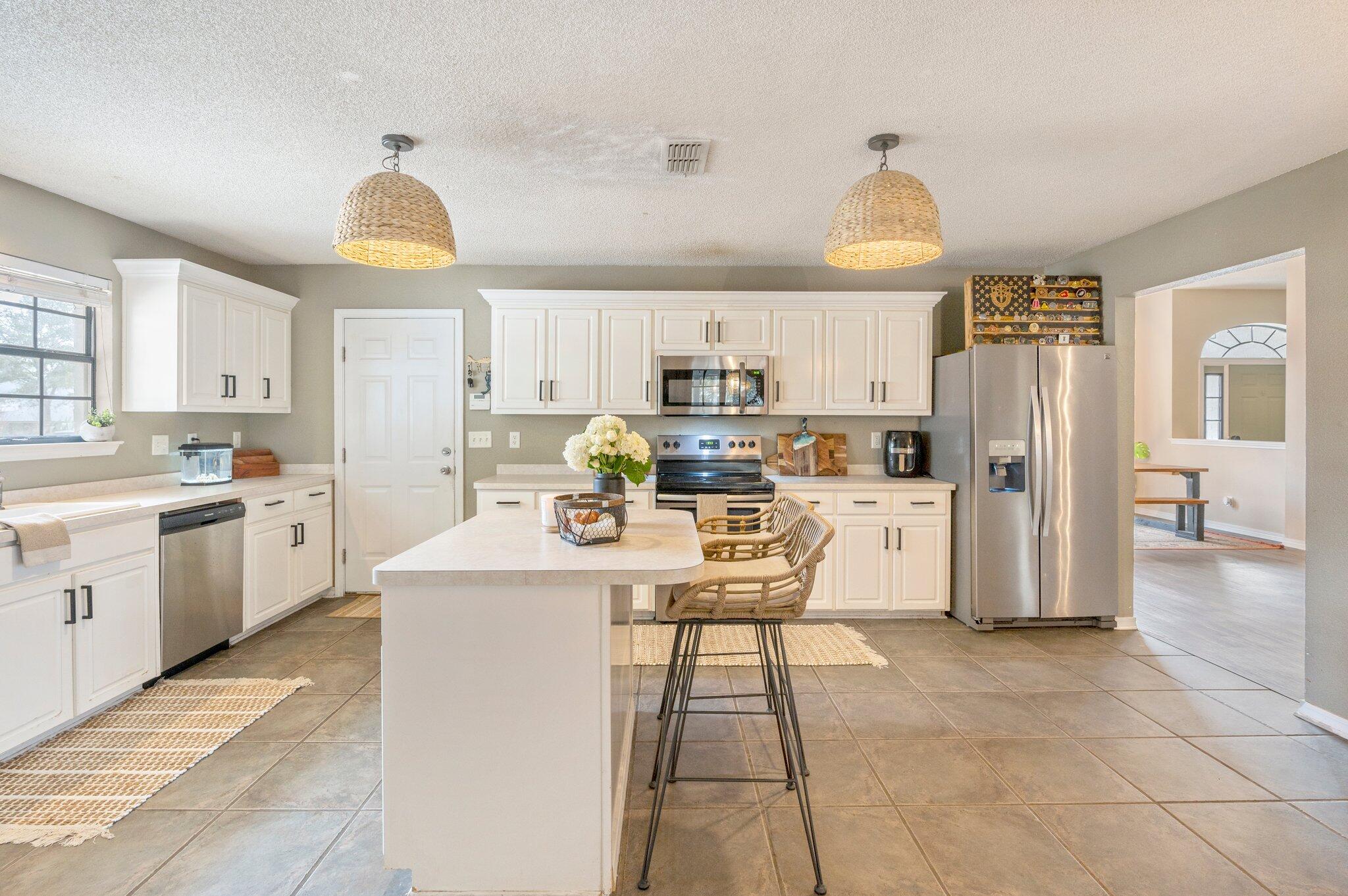 5938 Ridgeview Drive Milton, FL 32570 - Photo 18 of 58 a kitchen with stainless steel appliances a refrigerator a stove a sink a dining table and chairs