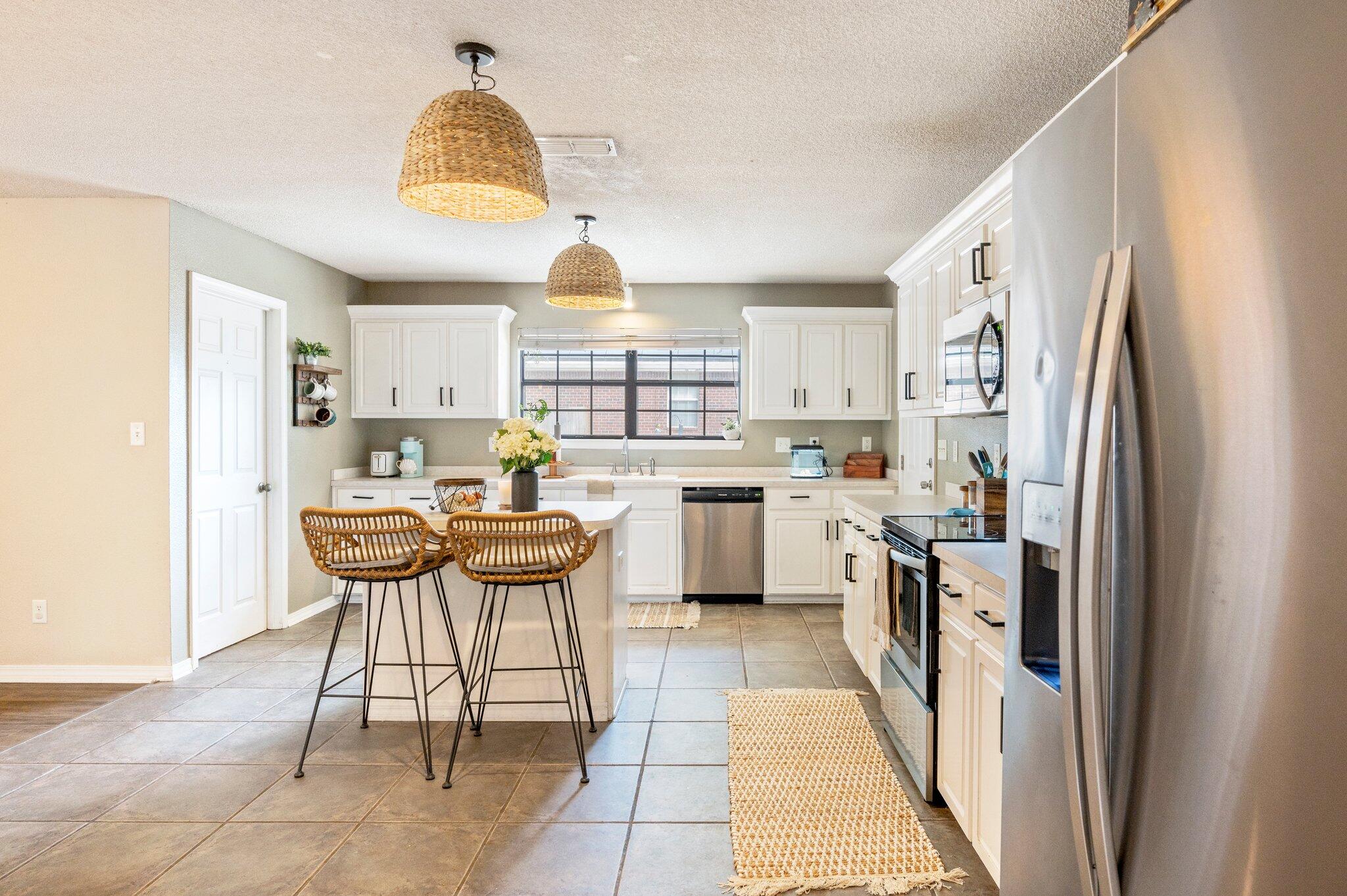 5938 Ridgeview Drive Milton, FL 32570 - Photo 25 of 58 a kitchen with stainless steel appliances a table chairs refrigerator and cabinets