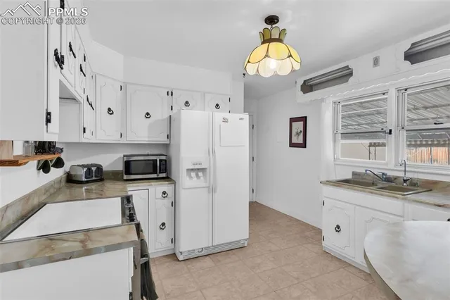 a kitchen with stainless steel appliances granite countertop a sink a stove a refrigerator and a chandelier