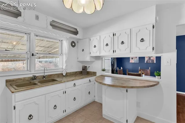 a kitchen with granite countertop a sink white cabinets with a large window