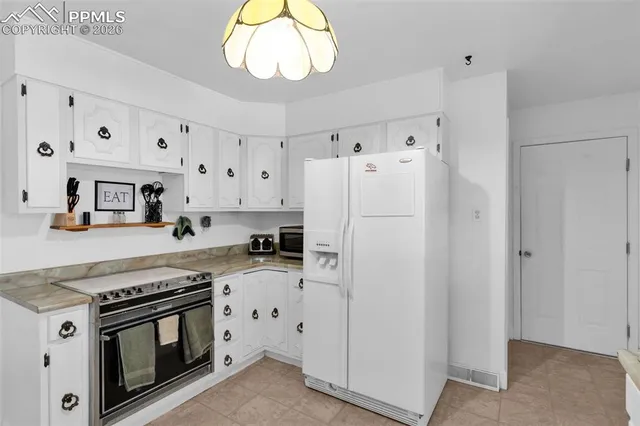 a white kitchen with a stove a refrigerator and a sink