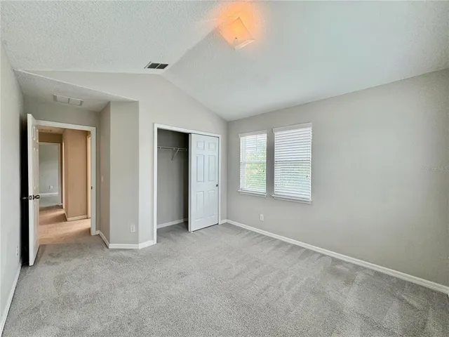 a view of an empty room with closet and a window