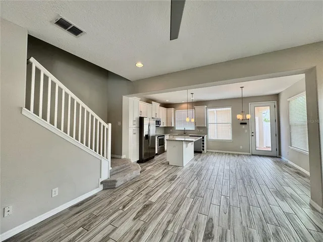 a view of a livingroom with wooden floor and electronic appliances