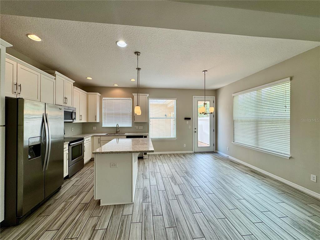 8620 Wellington Blue Lane Windermere, FL 34786 - Photo 7 of 22 a kitchen with stainless steel appliances a refrigerator a sink dishwasher a stove and white countertops with wooden floor
