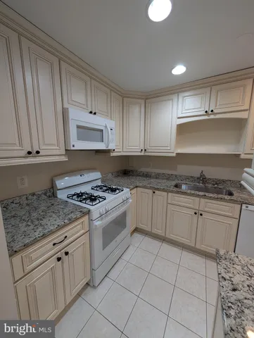a kitchen with granite countertop white cabinets and white appliances