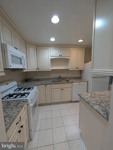 a kitchen with granite countertop white cabinets and appliances