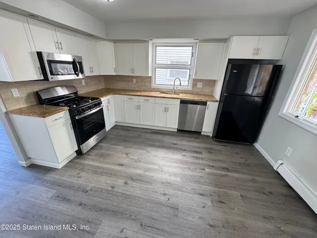 a kitchen with a sink wooden floor and black appliances