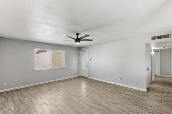 an empty room with wooden floor fan and windows