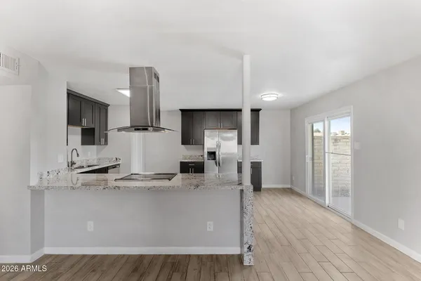 a large kitchen with stainless steel appliances kitchen island granite countertop a stove a sink a refrigerator and white cabinets with wooden floor