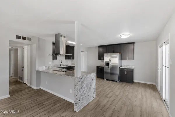 a kitchen with stainless steel appliances kitchen island granite countertop a refrigerator oven a sink dishwasher and a stove with wooden floor