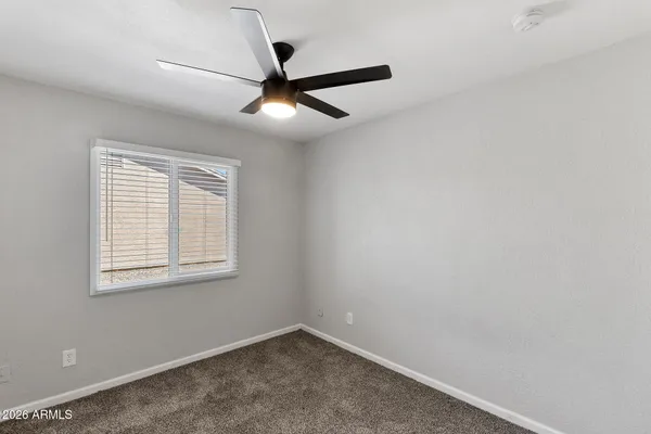 an empty room with a window and a fan