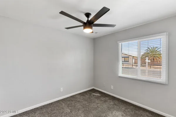 an empty room with a window and ceiling fan
