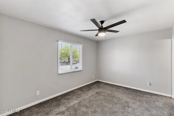 an empty room with a window and a fan