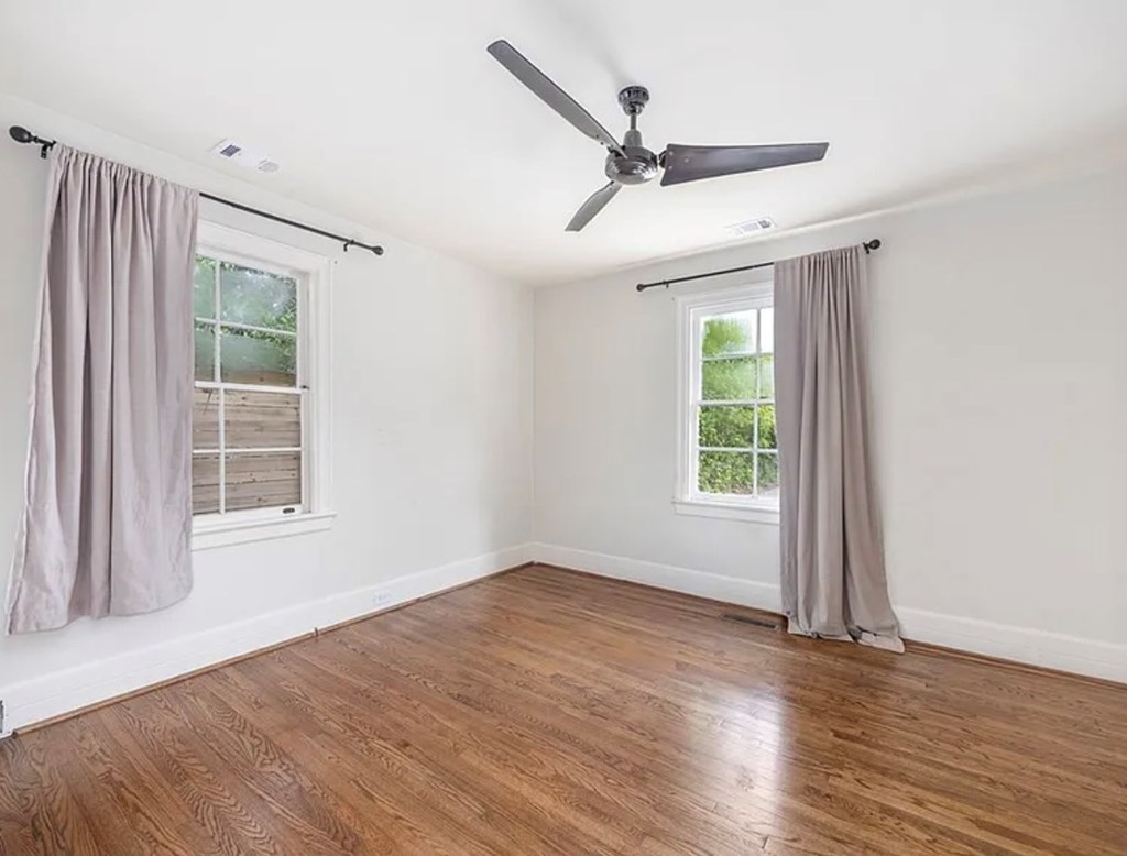 1312 10th Street, Unit B Columbus, GA 31906 - Photo 5 of 11 an empty room with wooden floor fan and windows