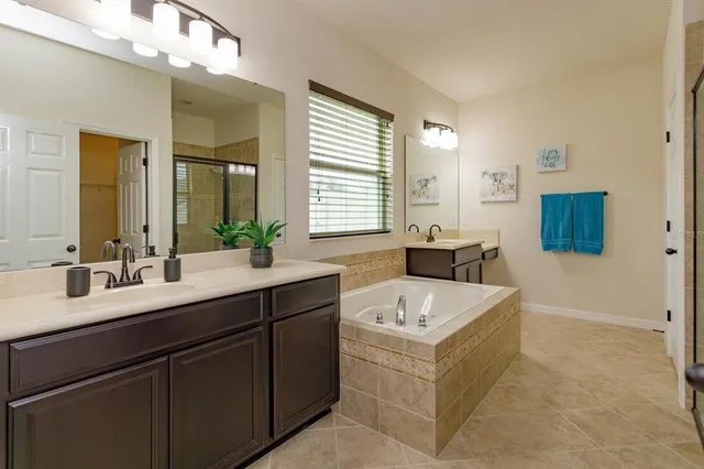 a spacious bathroom with a tub sink and mirror