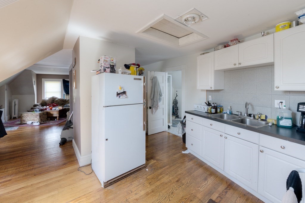 407-9 Sumner Avenue Springfield, MA 01108 - Photo 31 of 40 a kitchen with sink a refrigerator and white cabinets with wooden floor