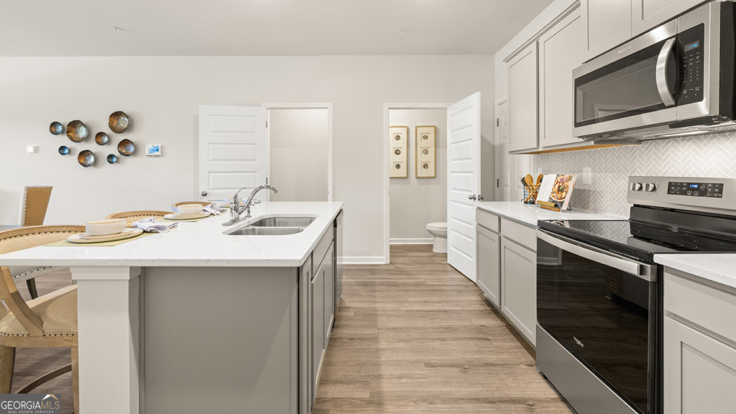 404 Reflection Drive Stockbridge, GA 30281 - Photo 17 of 57 a kitchen with stainless steel appliances granite countertop a sink and dishwasher a stove top oven with wooden floor