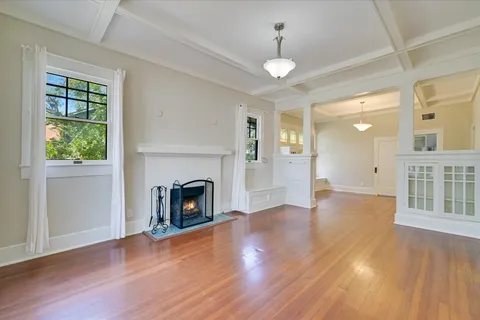 a view of a livingroom with wooden floor a fireplace and windows