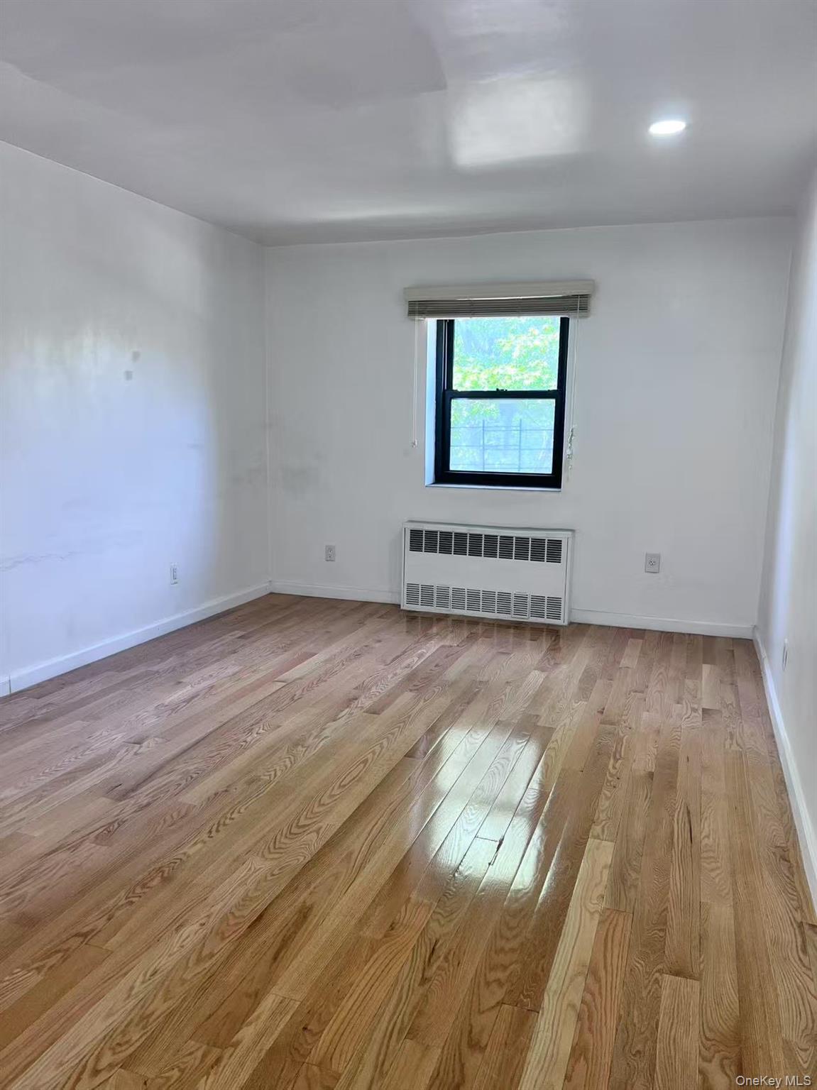 138-20 31st Road, Unit 2C Queens, NY 11354 - Photo 5 of 6 an empty room with wooden floor and windows