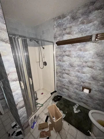 a bathroom with a granite countertop bathtub shower sink mirror and toilet