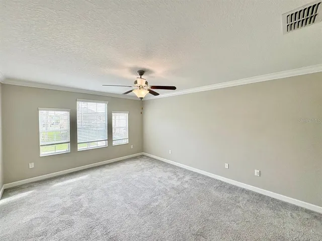 an empty room with windows and ceiling fan