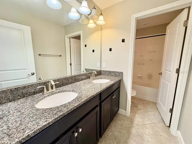 a bathroom with a granite countertop sink a mirror and a shower