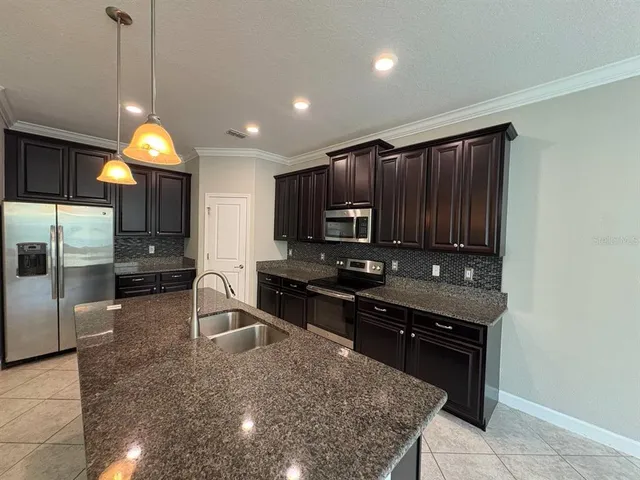 a kitchen with stainless steel appliances granite countertop a sink a stove and a refrigerator