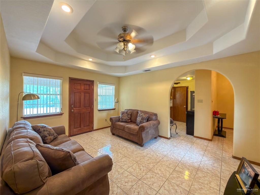 7435 Dillon Road Donna, TX 78537 - Photo 6 of 17 Living area featuring a tray ceiling with recessed lighting and a ceiling fan, ceramic tile flooring, a solid wood entry door, and arched doorways