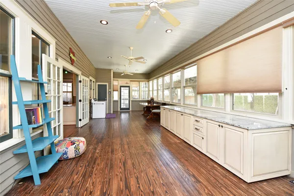 a large white kitchen with stainless steel appliances wooden floors and view living room