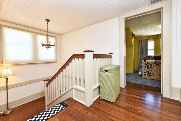 a hallway with wooden floor and stairs
