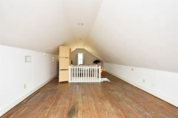 a bedroom with a bed and a night stand with wooden floor