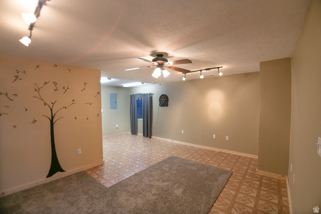 348 North Jakes Pl Road Loa, UT 84747 - Photo 12 of 26 Spare room featuring rail lighting, a ceiling fan, light flooring, electric panel, and a textured ceiling