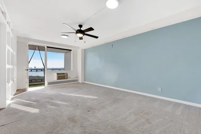 an empty room with chandelier fan and windows