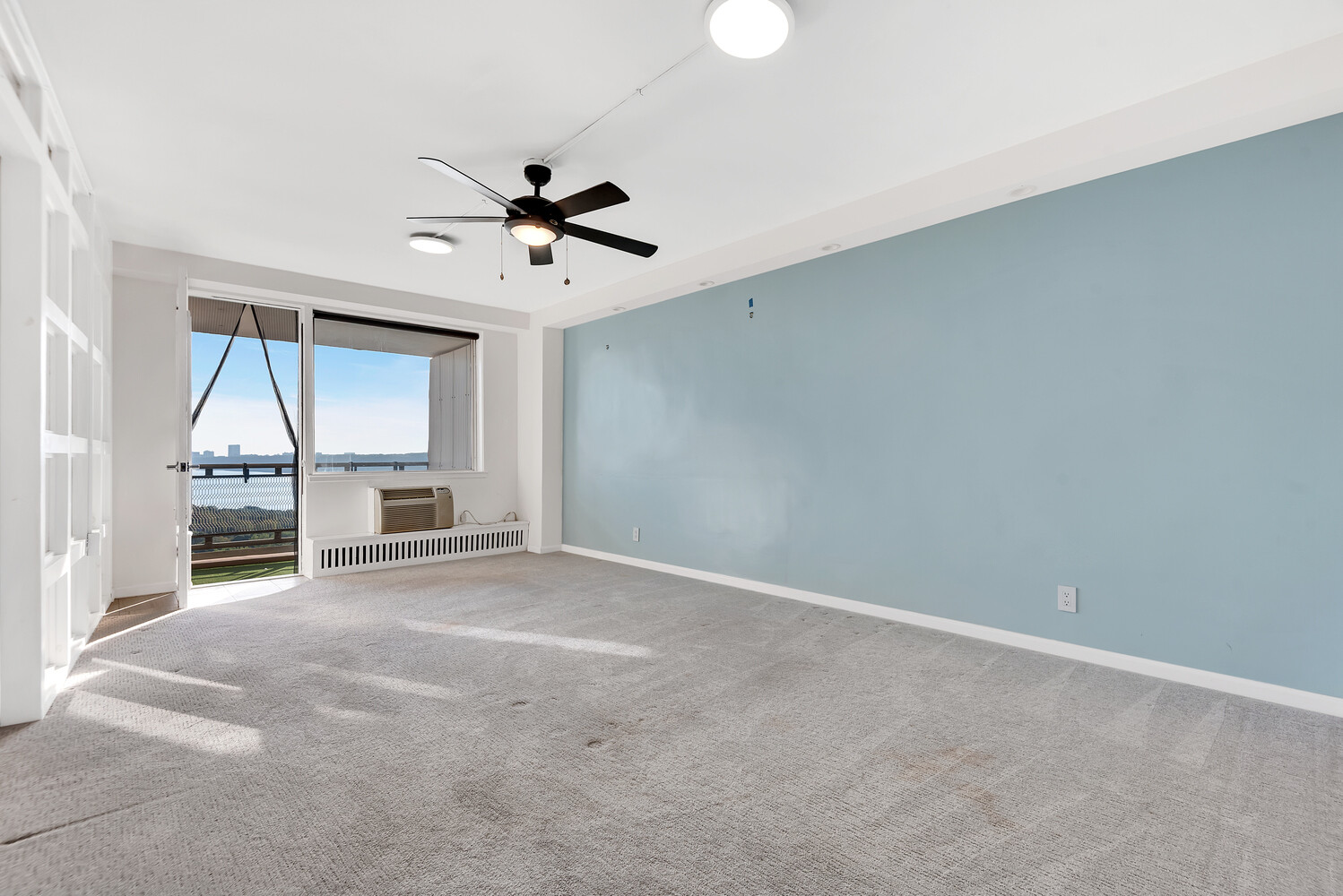 an empty room with chandelier fan and windows