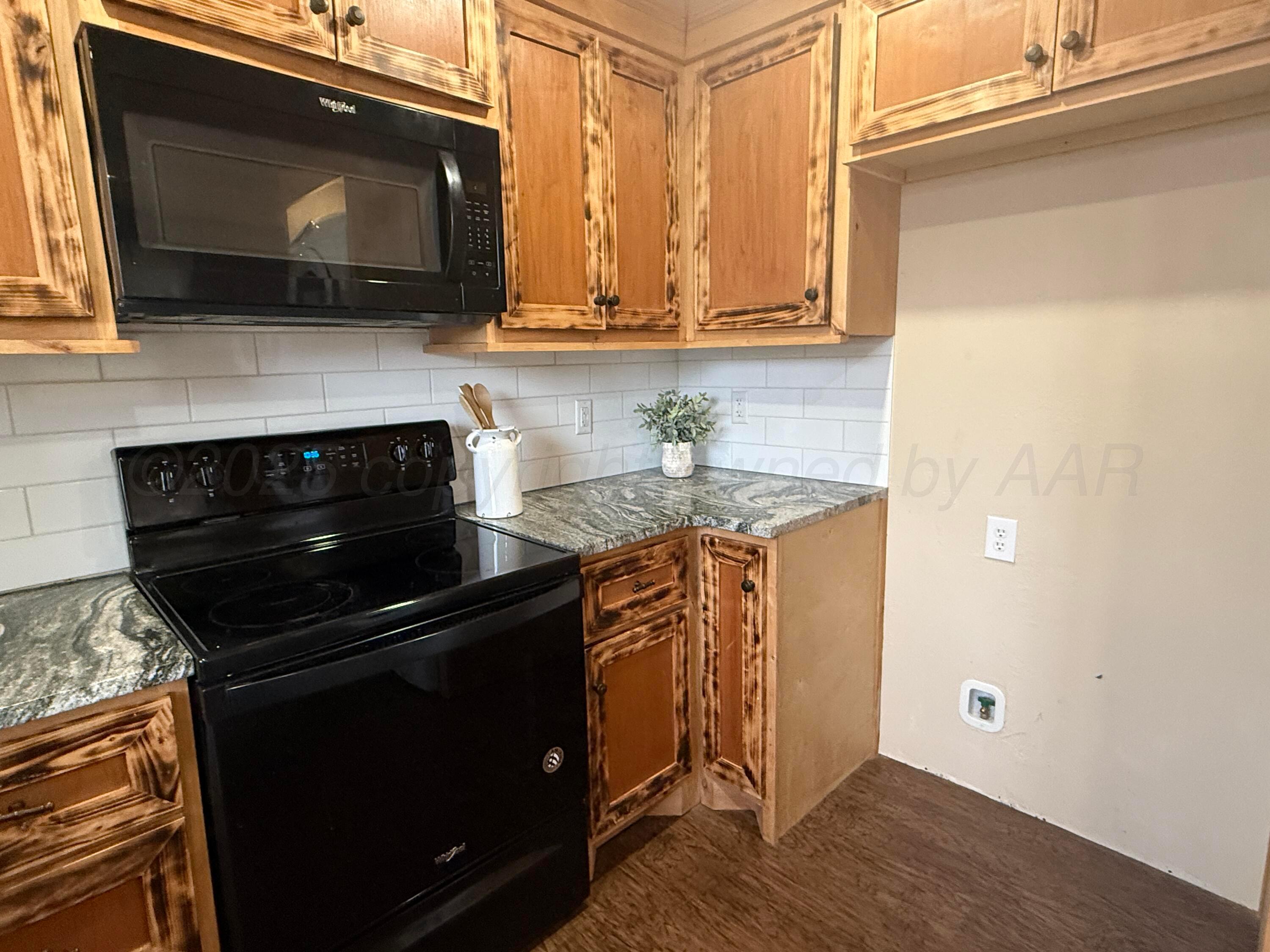 701 East 3rd Street Dumas, TX 79029 - Photo 5 of 14 a kitchen with stainless steel appliances a stove a microwave a sink and cabinets