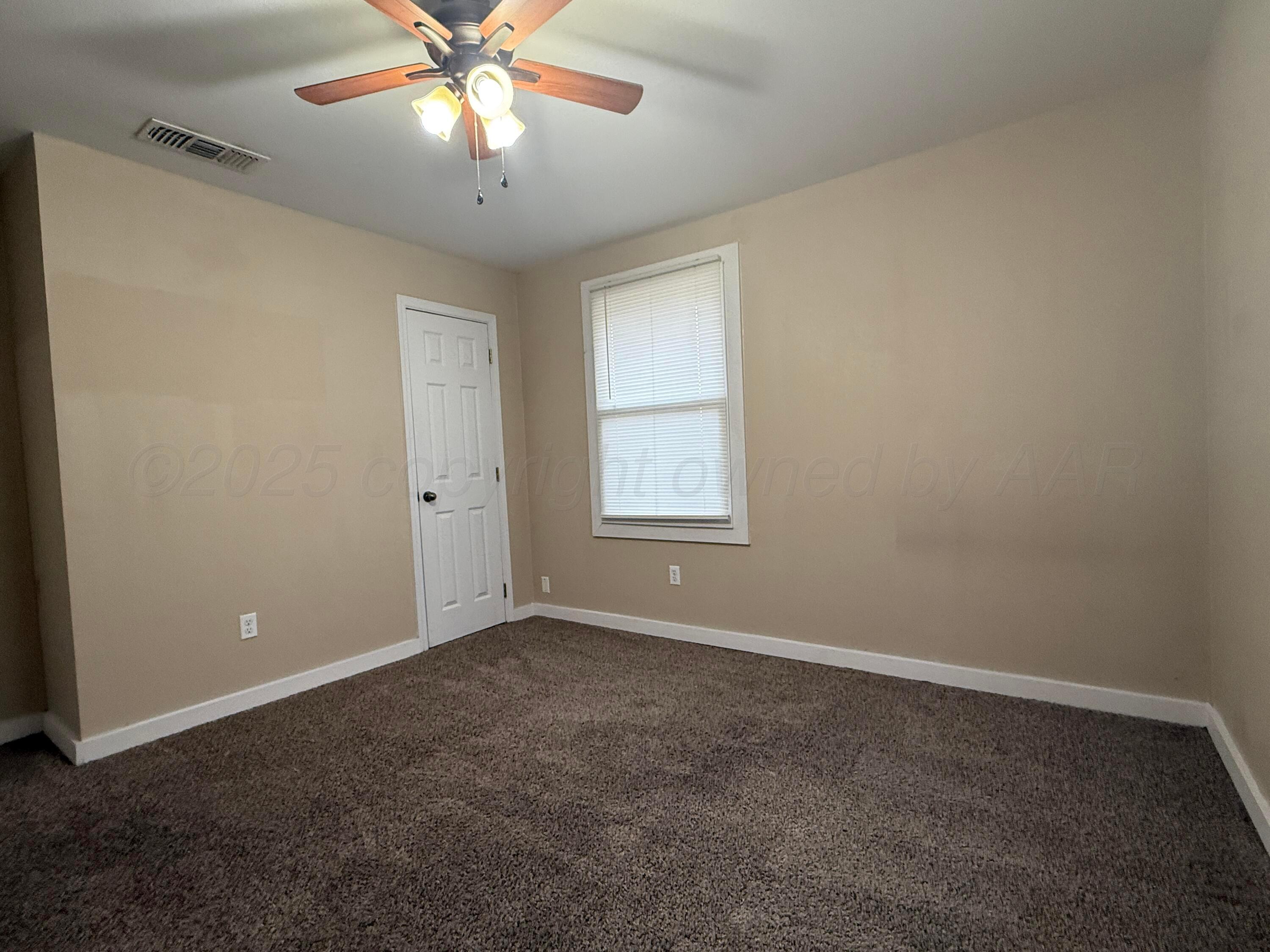 701 East 3rd Street Dumas, TX 79029 - Photo 7 of 14 an empty room with windows and fan