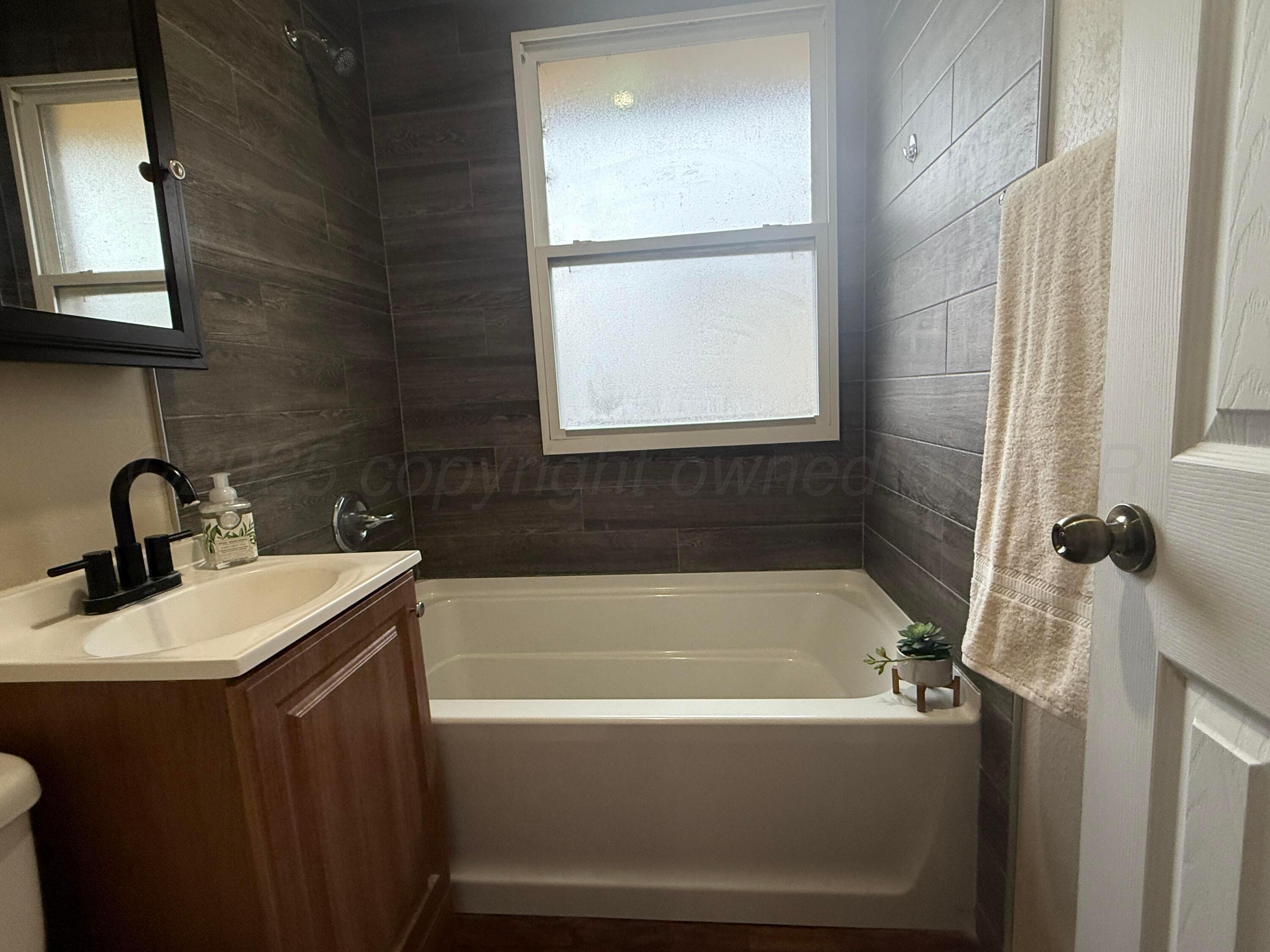 701 East 3rd Street Dumas, TX 79029 - Photo 8 of 14 a bathroom with a sink a bathtub and a window