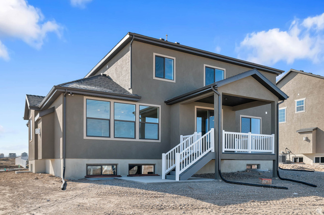 562 West Coyote Rdg Road Grantsville, UT 84029 - Photo 6 of 27 Stucco exterior with multiple large windows, covered patio, white railing, and a walkout basement