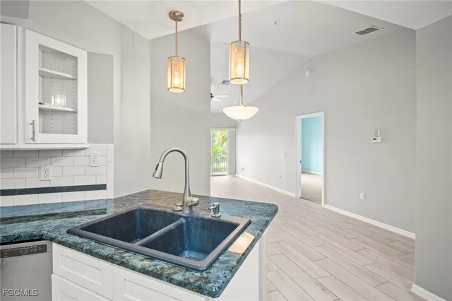 a kitchen with granite countertop a sink a counter space appliances and cabinets