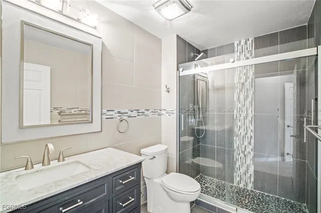 a bathroom with a shower sink vanity mirror and toilet