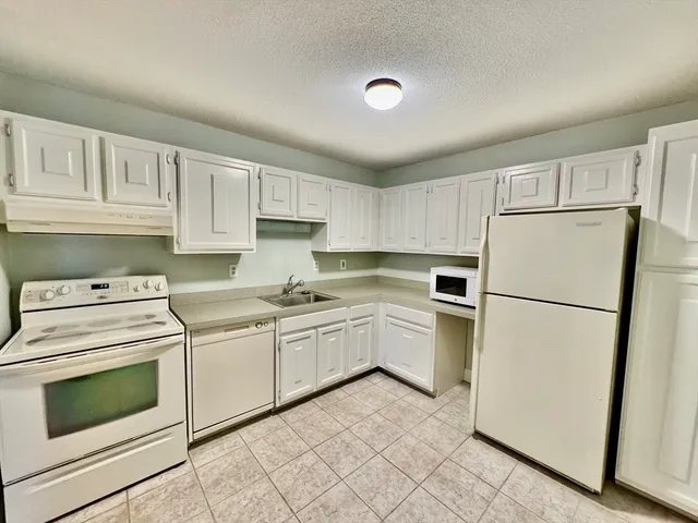 a kitchen with white cabinets and white appliances