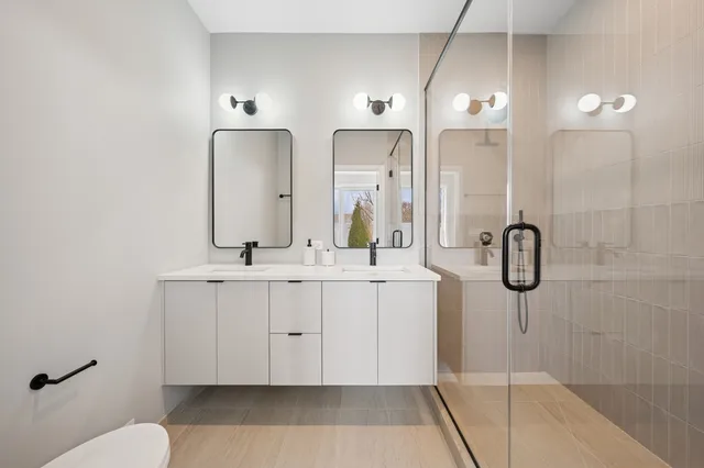 a bathroom with a double vanity sink mirror and shower