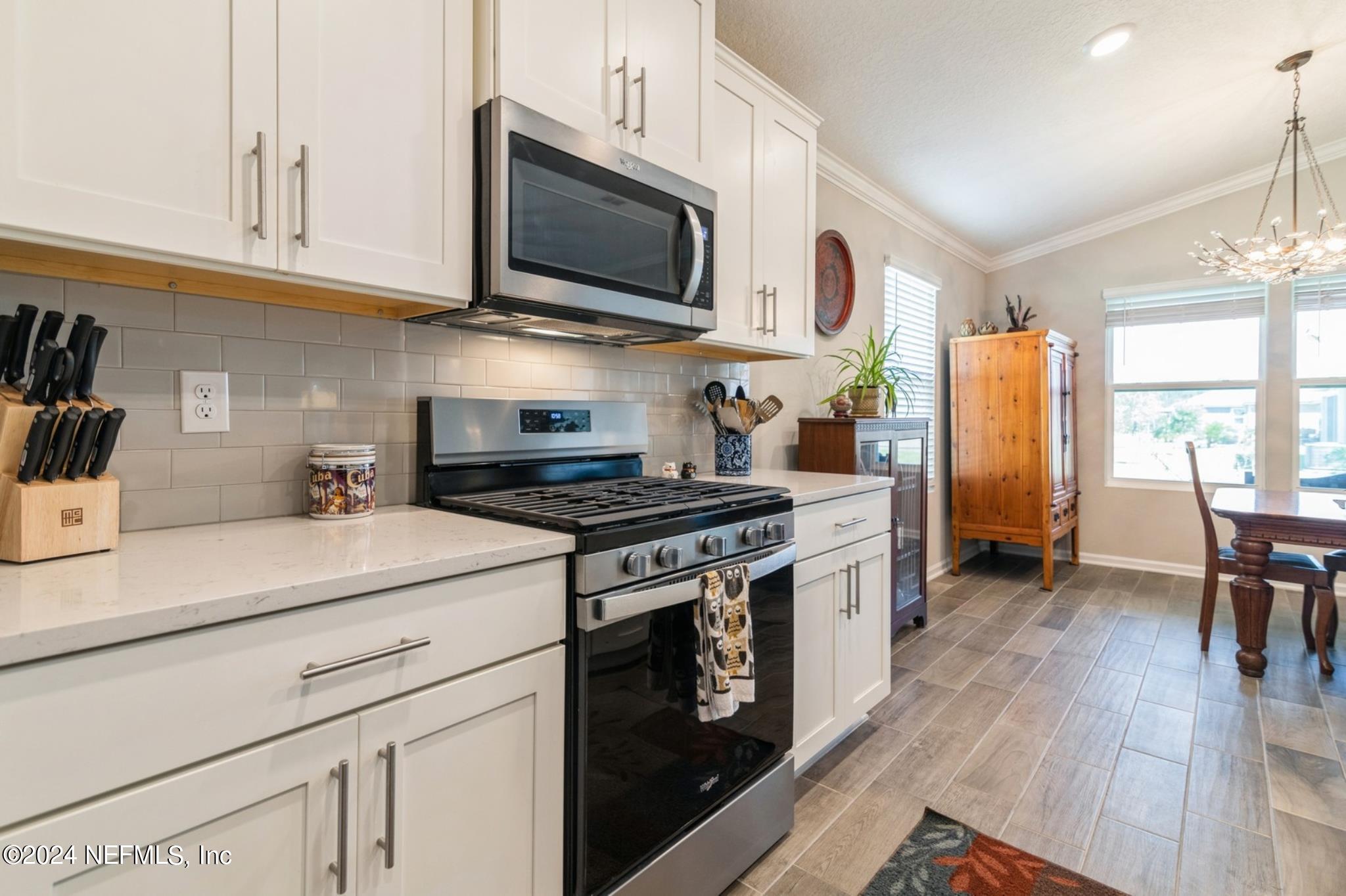 97 Spotted Owl Lane St. Augustine, FL 32095 - Photo 16 of 38 a kitchen with stainless steel appliances granite countertop a sink a stove a microwave a refrigerator a dining table and chairs with wooden floor